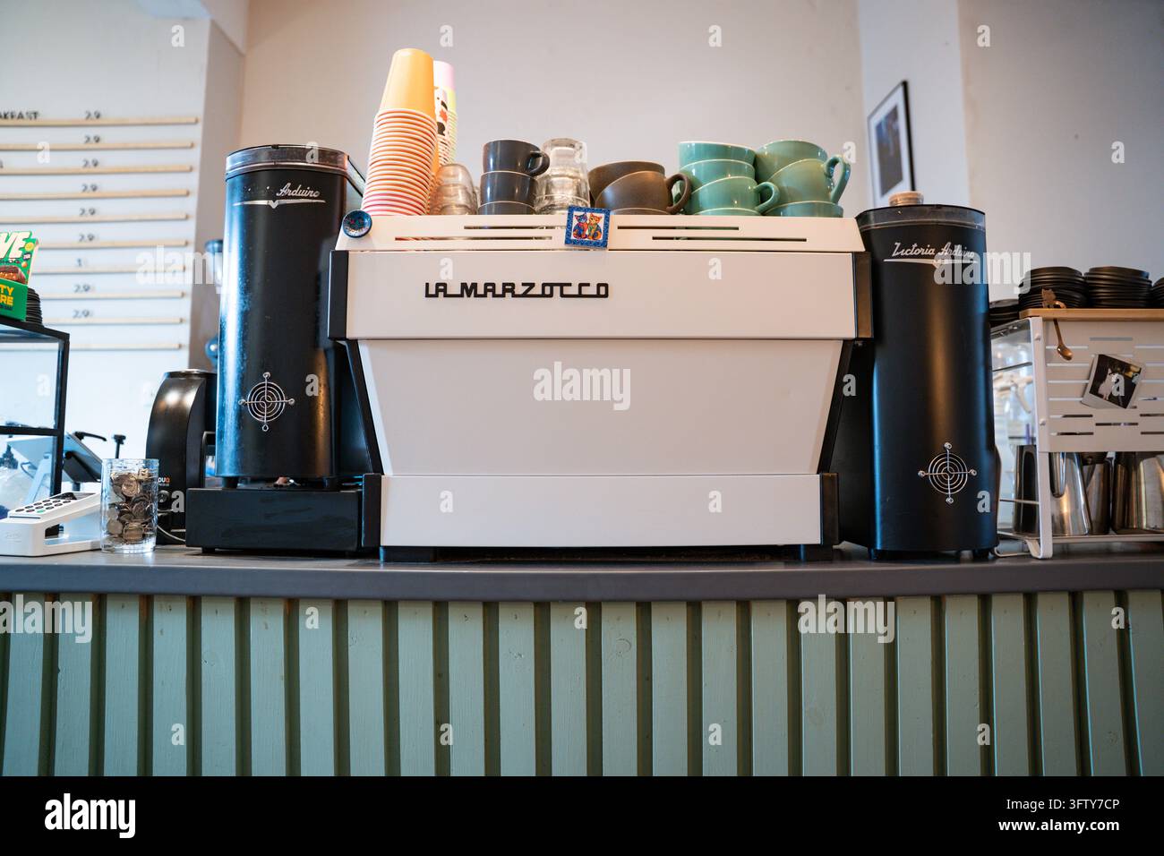 Macchina da caffè La Marzocco su un bancone del caffè con macinacaffè Victoria Arduino e tazze impilate Foto Stock
