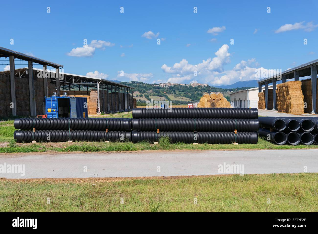 Pile di tubi di drenaggio in plastica ondulata nera nel cortile di stoccaggio della fattoria Foto Stock