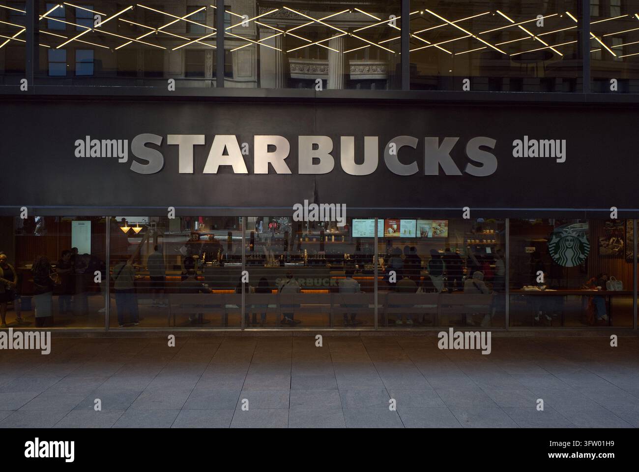 Il logo di Starbucks è esposto all'esterno di uno dei negozi della catena di caffetterie nel centro di Manhattan, evidenziando la presenza dell'azienda globale del caffè a NY. Foto Stock