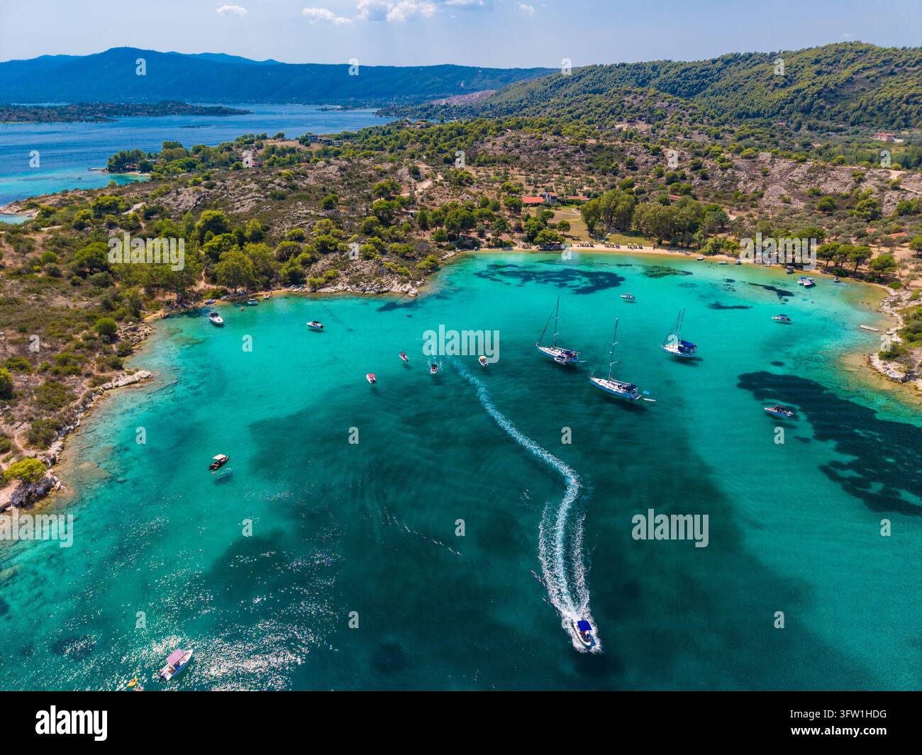 Risveglio del motoscafo che curva oltre le barche a vela, Galini, Calcidica, Grecia Foto Stock