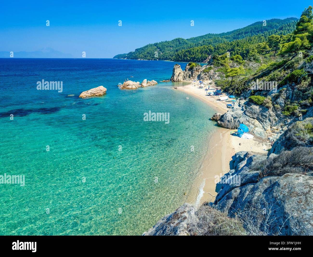 Stretta striscia di sabbia sotto colline boschive, spiaggia di Fava, Calcidica, Grecia Foto Stock
