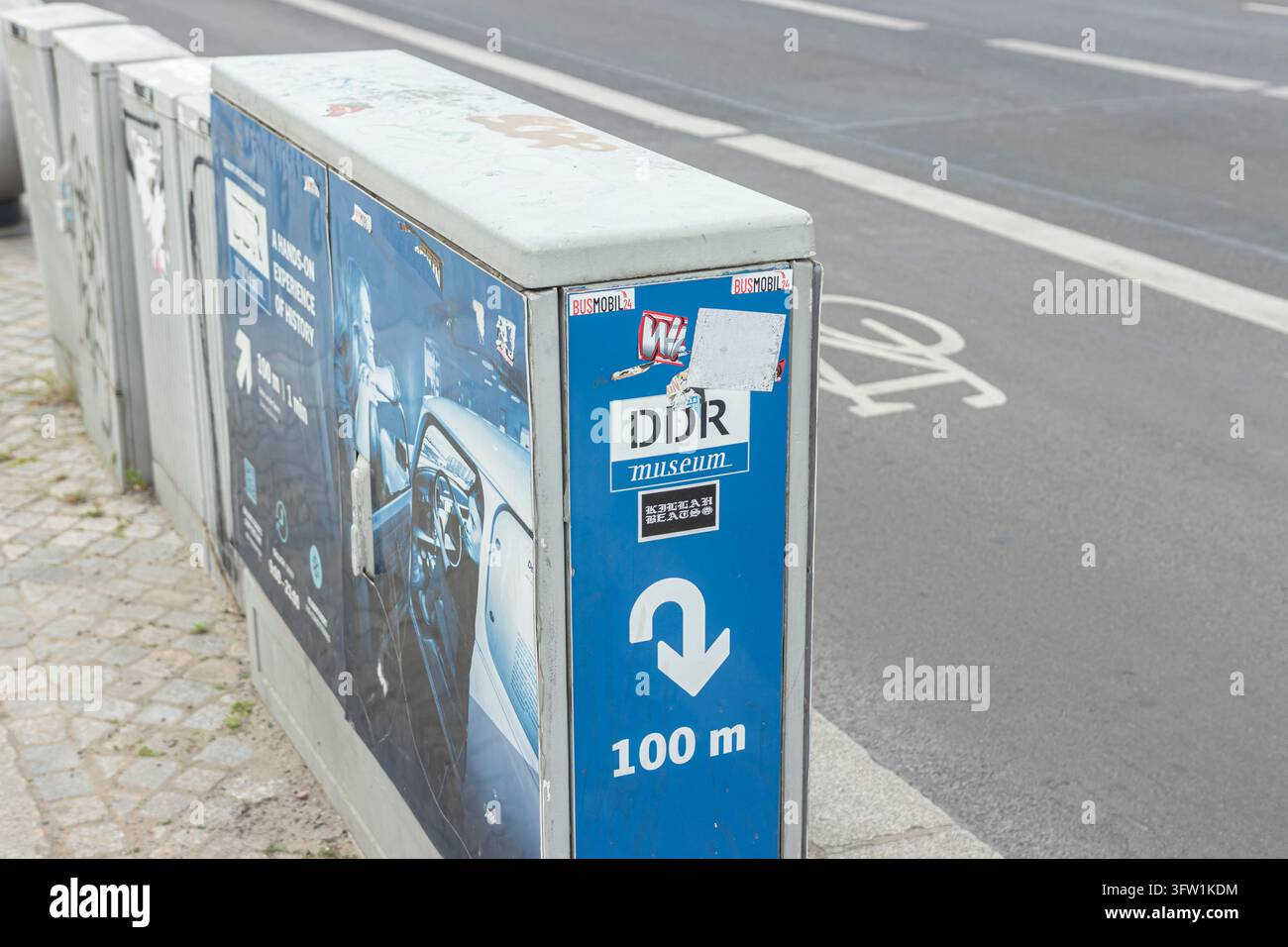 Germania, Berlino 2024 05 18: Cassette di distribuzione stradale con poster e adesivi del Museo DDR, vista ad angolo alto. Foto Stock