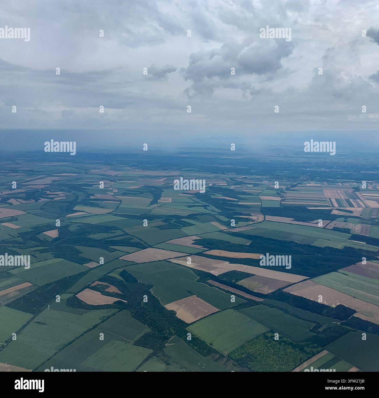 Veduta aerea di campi agricoli verdi a chiazze e paesaggio rurale sotto un cielo nuvoloso Foto Stock