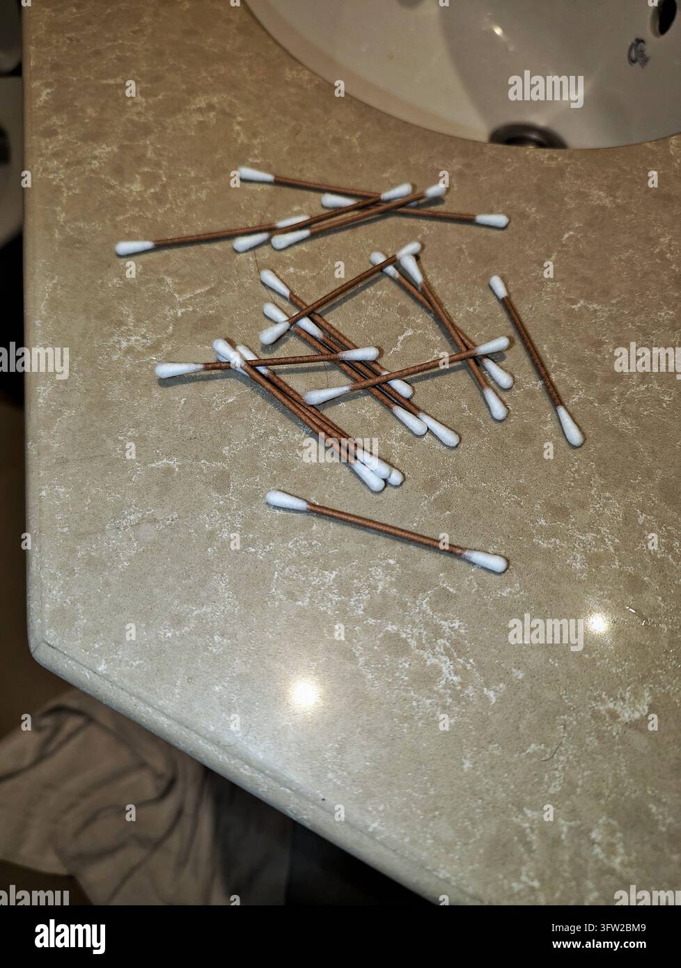 Tamponi di cotone sparsi con steli di carta marrone su un piano di bagno marmorizzato, 1 Foto Stock
