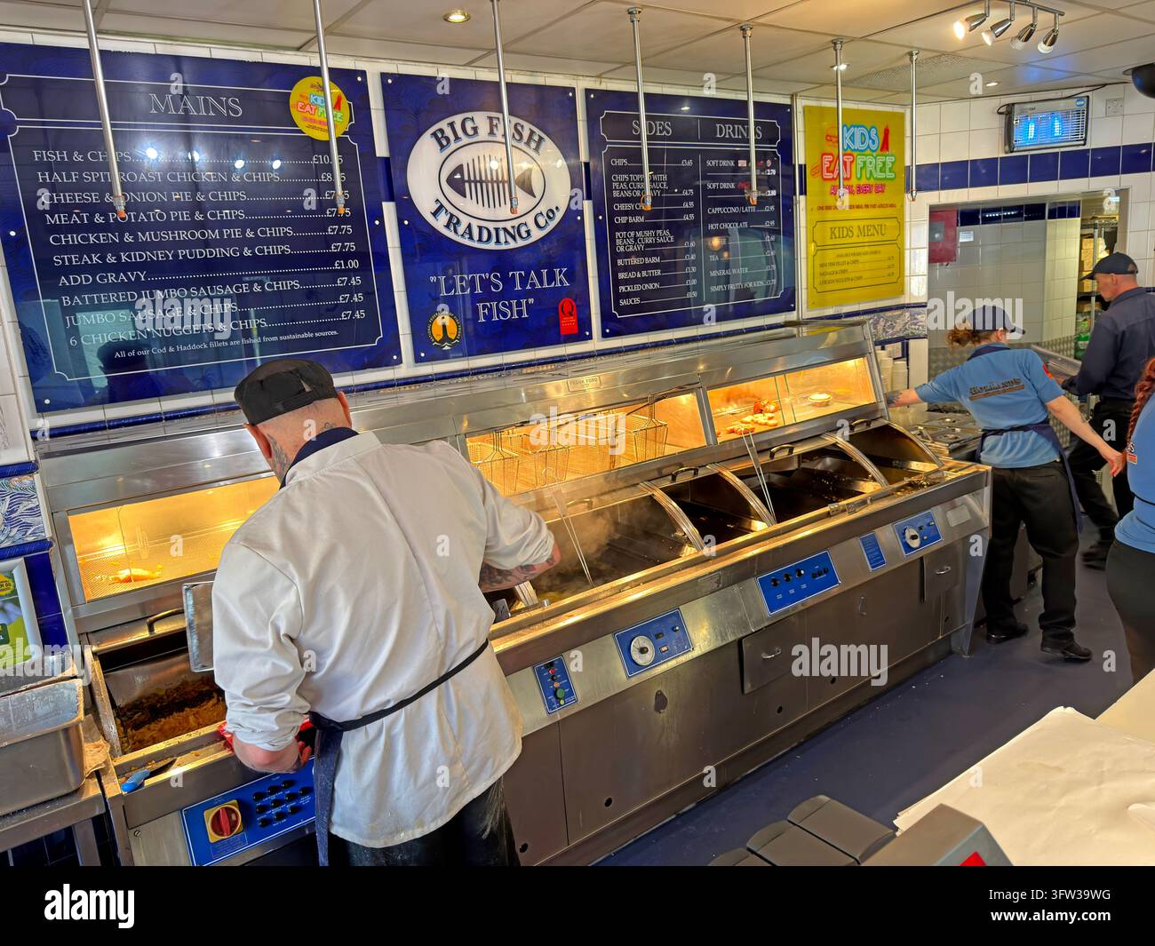 Un addetto di una friggitoria prepara il cibo dietro un bancone di servizio al Big Fish Trading Co di Blackpool. Foto Stock