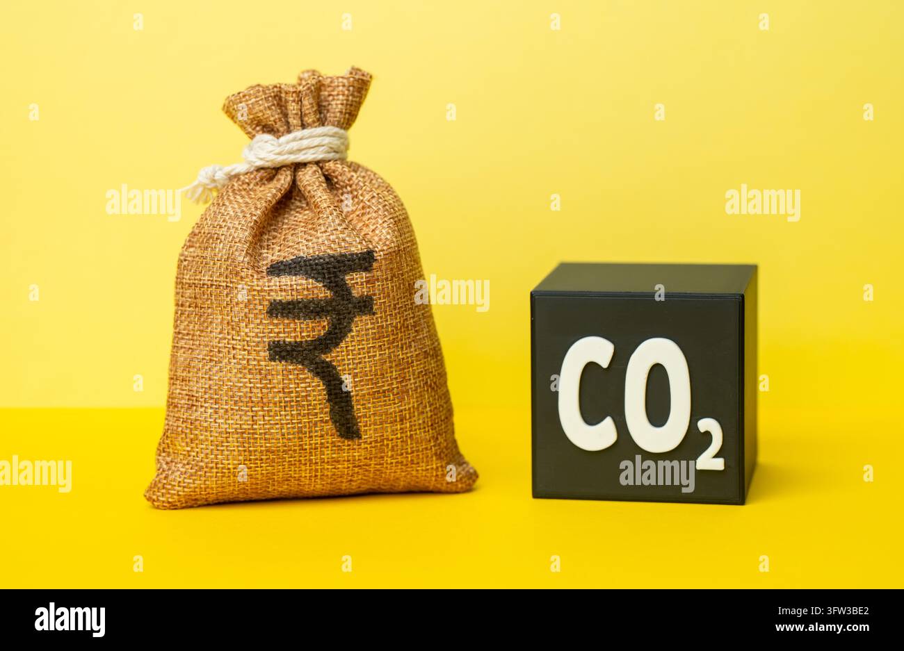 Un cubo di CO2 e un sacchetto di denaro indiano in rupie. Riciclaggio dei rifiuti e generazione di profitti. Riduzione dell’impatto ambientale generando reddito. Sovvenzioni al riciclaggio. Aumento del costo delle quote di emissione - Fotomontaggio Foto Stock