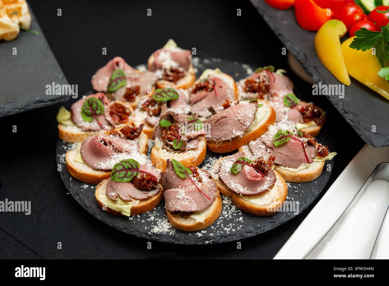 Canapè a faccia aperta guarniti con roast beef e formaggio sono disposti per il servizio. Foto Stock