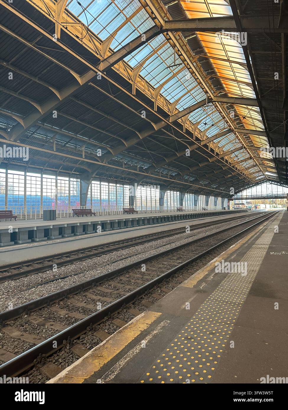 Binario della stazione ferroviaria vuoto con binari e tetto in vetro, vista prospettica. Foto Stock