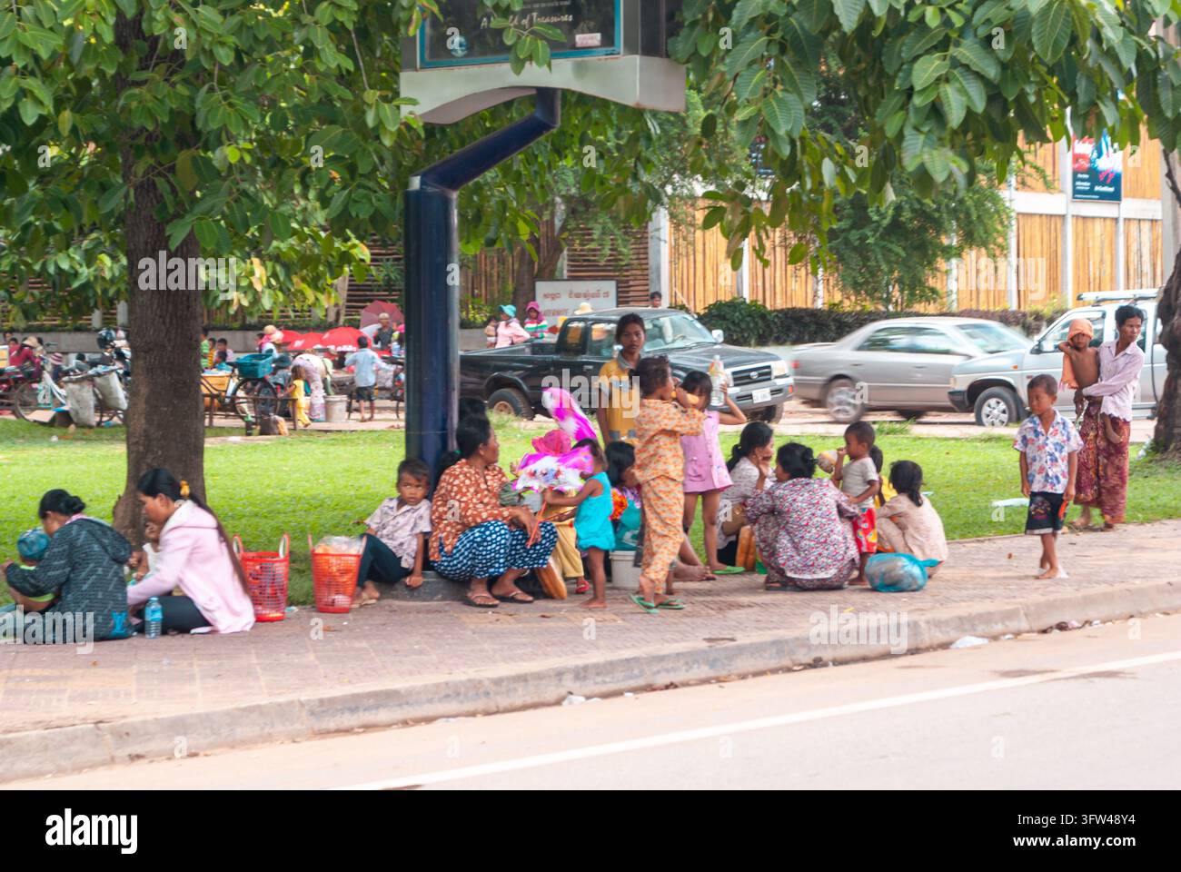 SIEM REAP, CAMBODIA - 28 LUGLIO 2011: Famiglie e bambini si radunano sotto gli alberi all'ombra in un parco pubblico a Siem Reap, Cambogia, socializzando, riposandosi Foto Stock