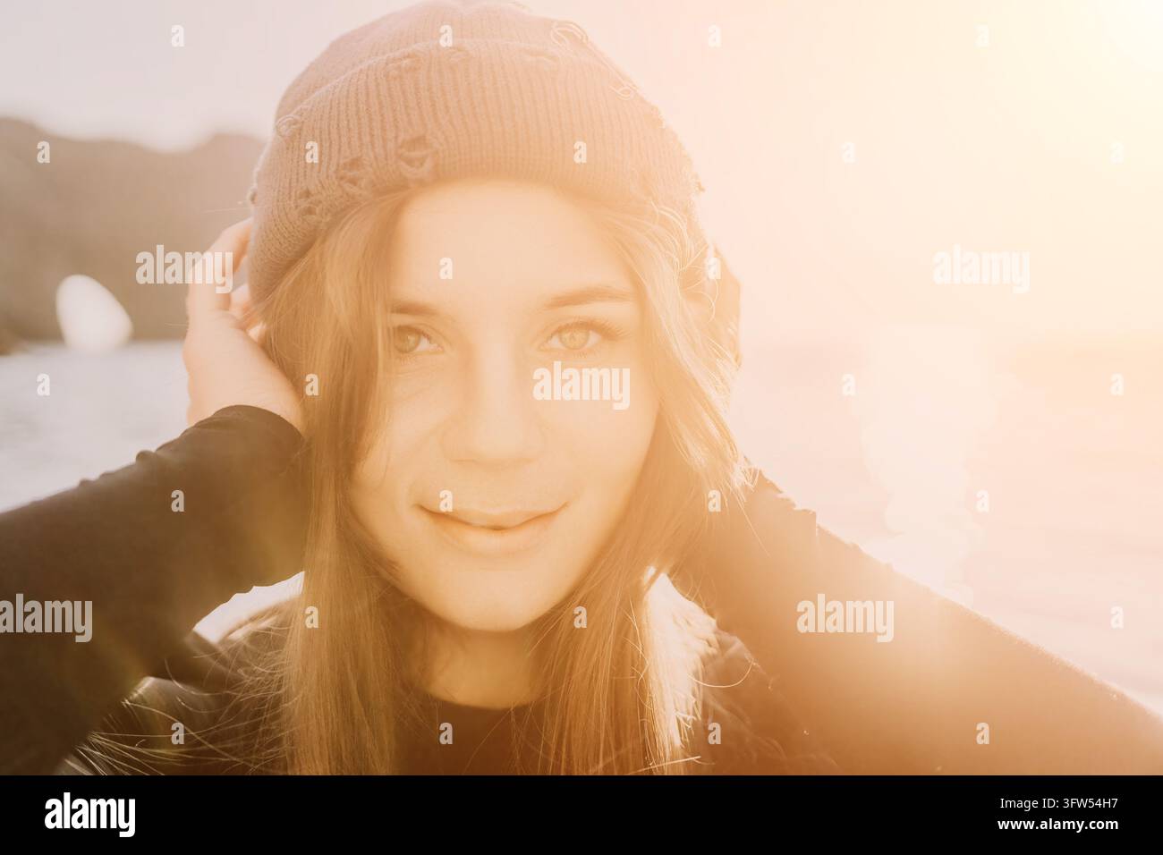 Donna, beanie, luce del sole, ritratto di una viaggiatrice sorridente con un cappello di lana all'aperto durante la luminosa ora dorata. Foto Stock