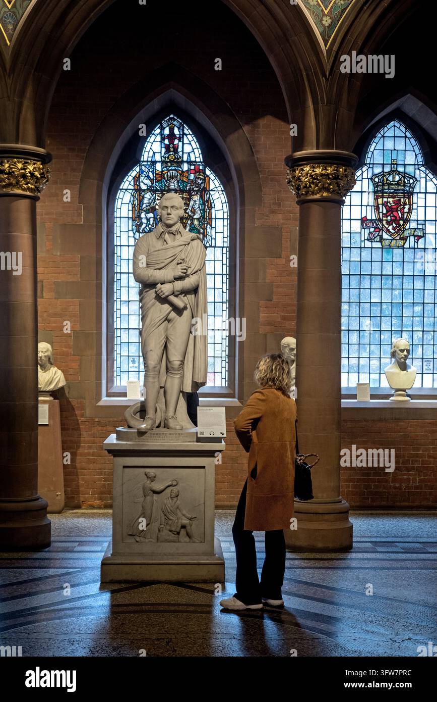 Visitatore della Scottish National Portrait Gallery che ammira la statua del poeta scozzese Robert Burns nel Great Hall. Foto Stock