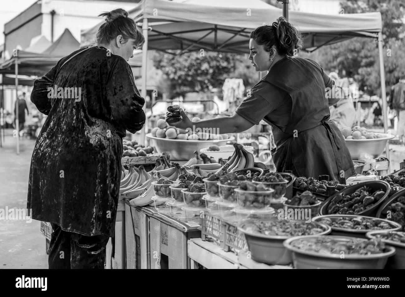 Un cliente e un venditore si scambiano merci a uno stand di prodotti freschi a Bukhara, Uzbekistan. Foto Stock
