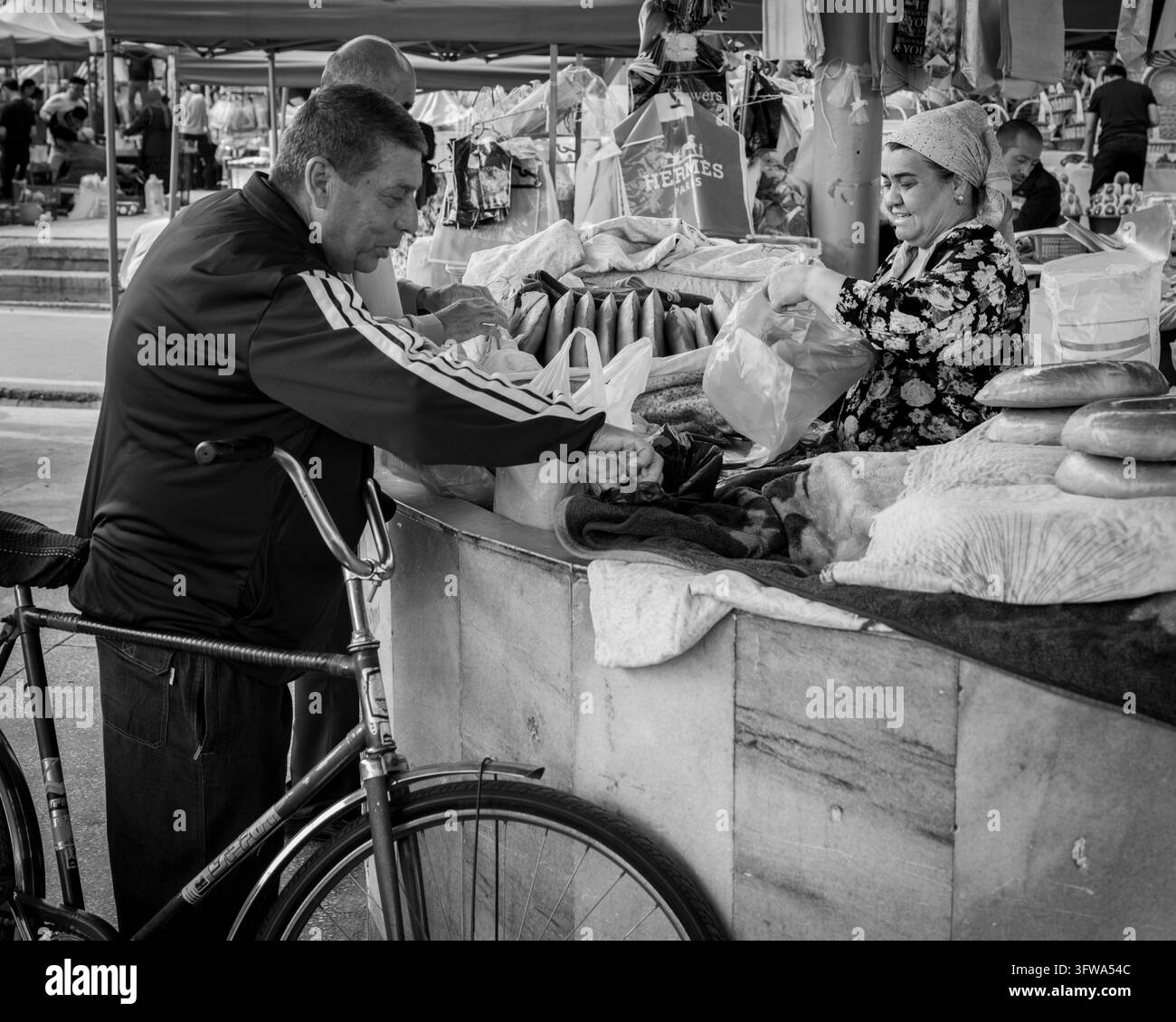 Un cliente con una bicicletta riceve merci da un venditore di pane in Uzbekistan. Foto Stock