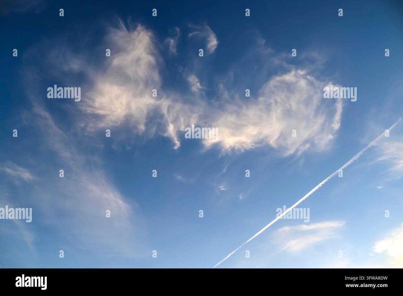 Una tela patinata di nuvole luminose dipinge il sereno cielo estivo Foto Stock