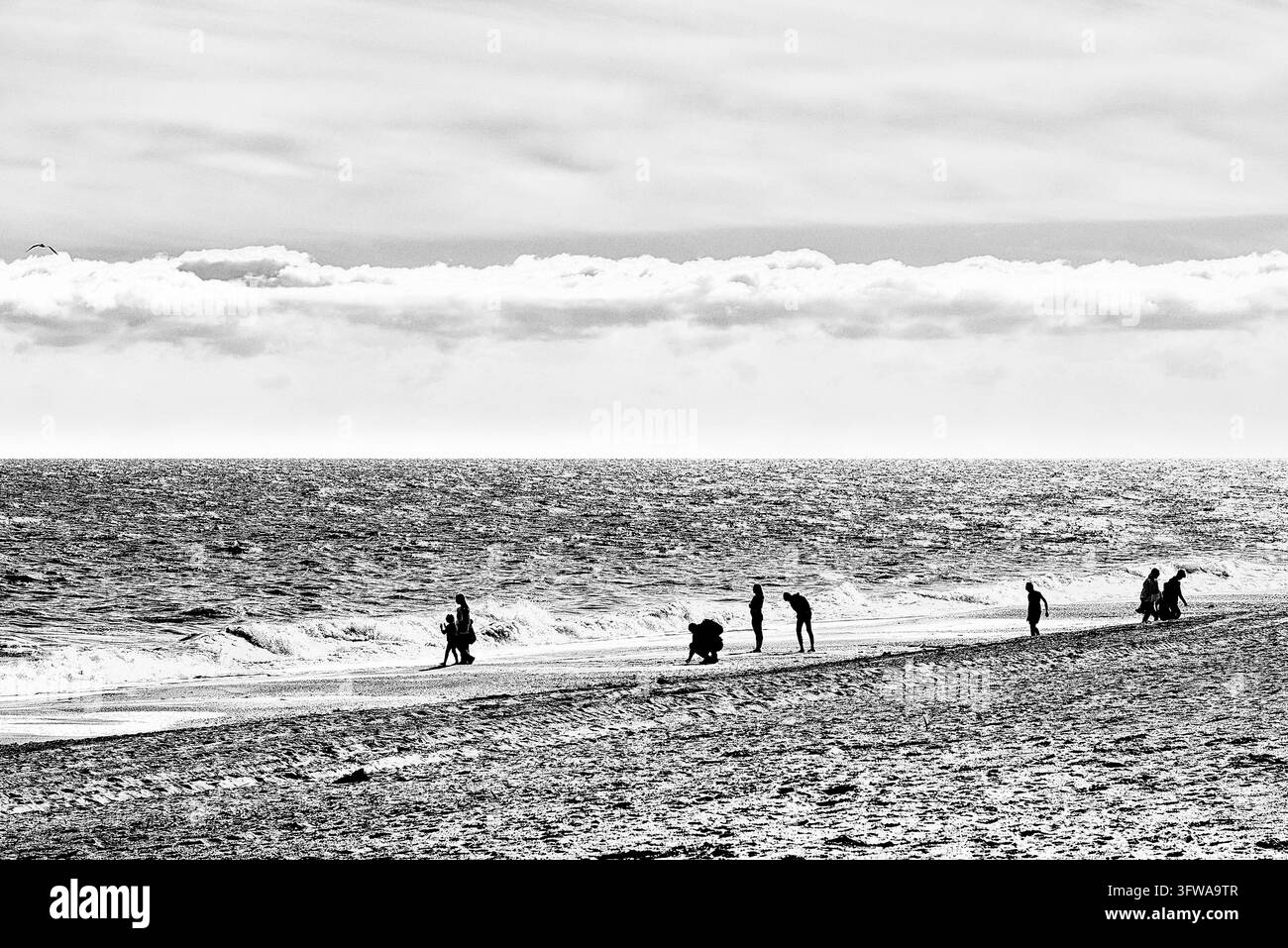 Persone che passeggiano lungo una spiaggia larga sotto una coltre di nuvole lungo il mare ondulato, San Luis de Sabinillas, Manilva, provincia di Malaga, Andalusia, Costa del Sol, Me Foto Stock