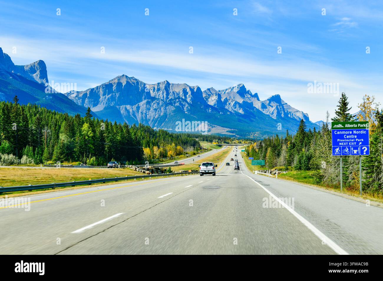 CANMORE, CANADA - 28 SET. 2026: Veicoli che viaggiano sull'Autostrada Trans-Canada oltre un cartello blu di Alberta Parks per il Canmore Nordic Centre Foto Stock