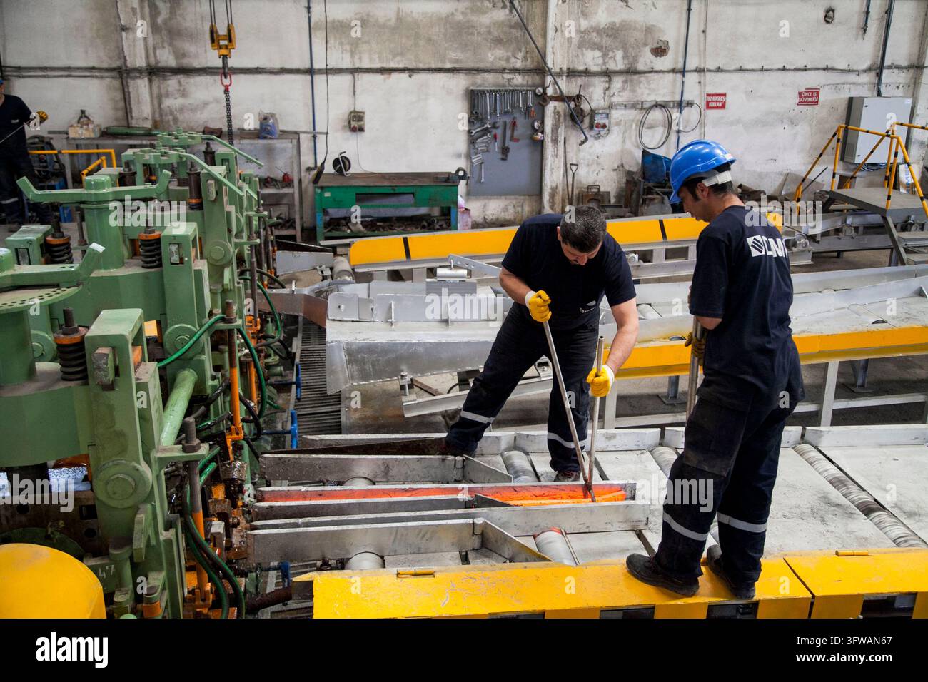 Gli operai gestiscono macchinari e monitorano il processo di produzione all'interno di un piccolo laminatoio a Dilovası, Kocaeli, Türkiye, il 16 maggio 2015. Foto Stock