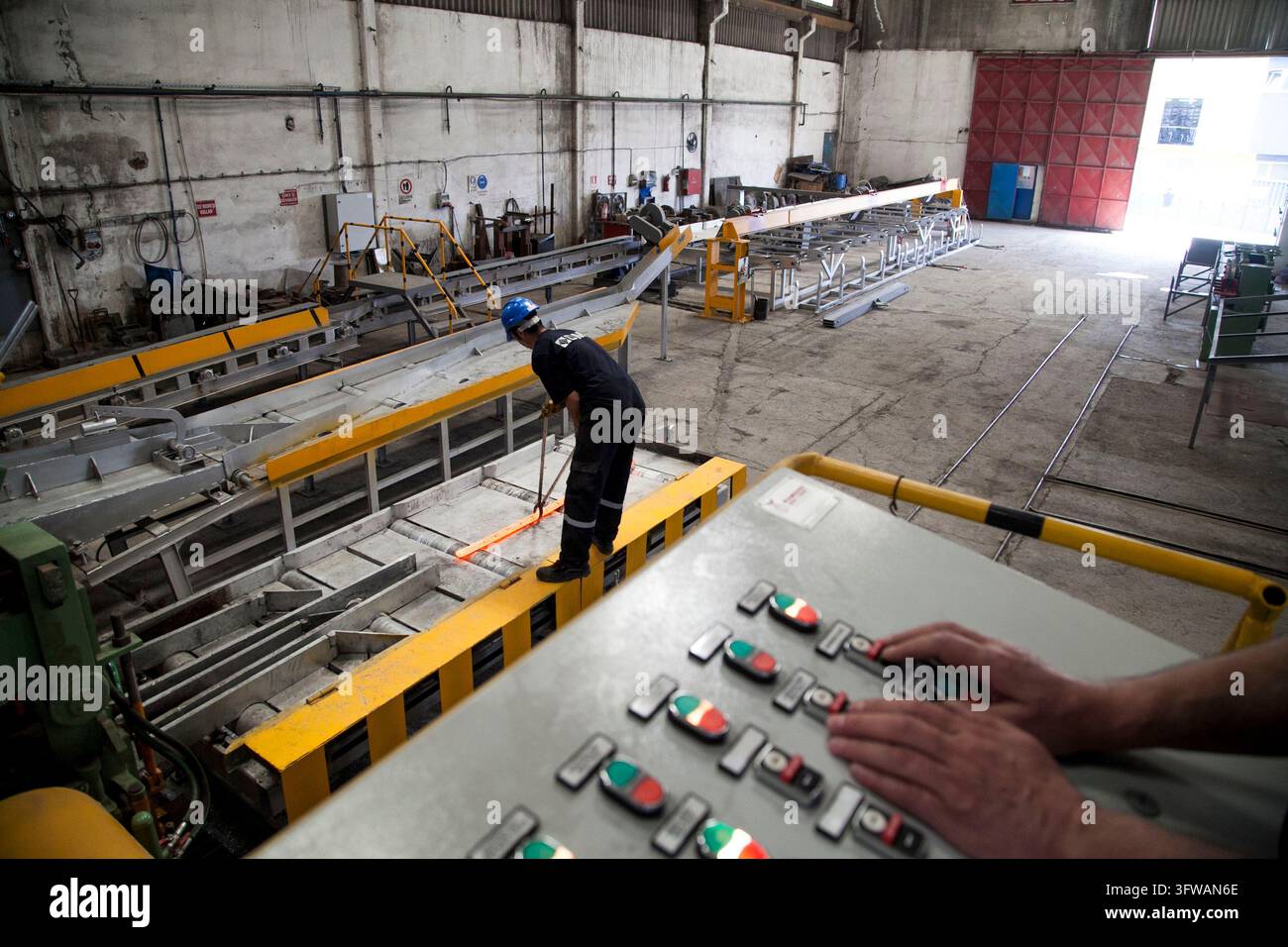 Gli operai gestiscono macchinari e monitorano il processo di produzione all'interno di un piccolo laminatoio a Dilovası, Kocaeli, Türkiye, il 16 maggio 2015. Foto Stock