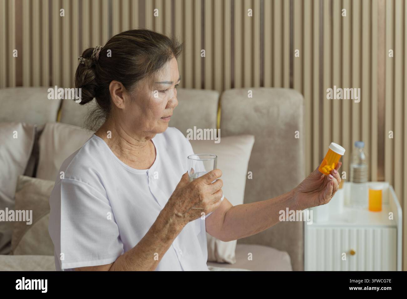 Anziana che rivede i suoi farmaci a casa, concentrandosi su salute e benessere. Ideale per concetti di assistenza sanitaria, invecchiamento e stile di vita degli anziani nei contenuti. Foto Stock