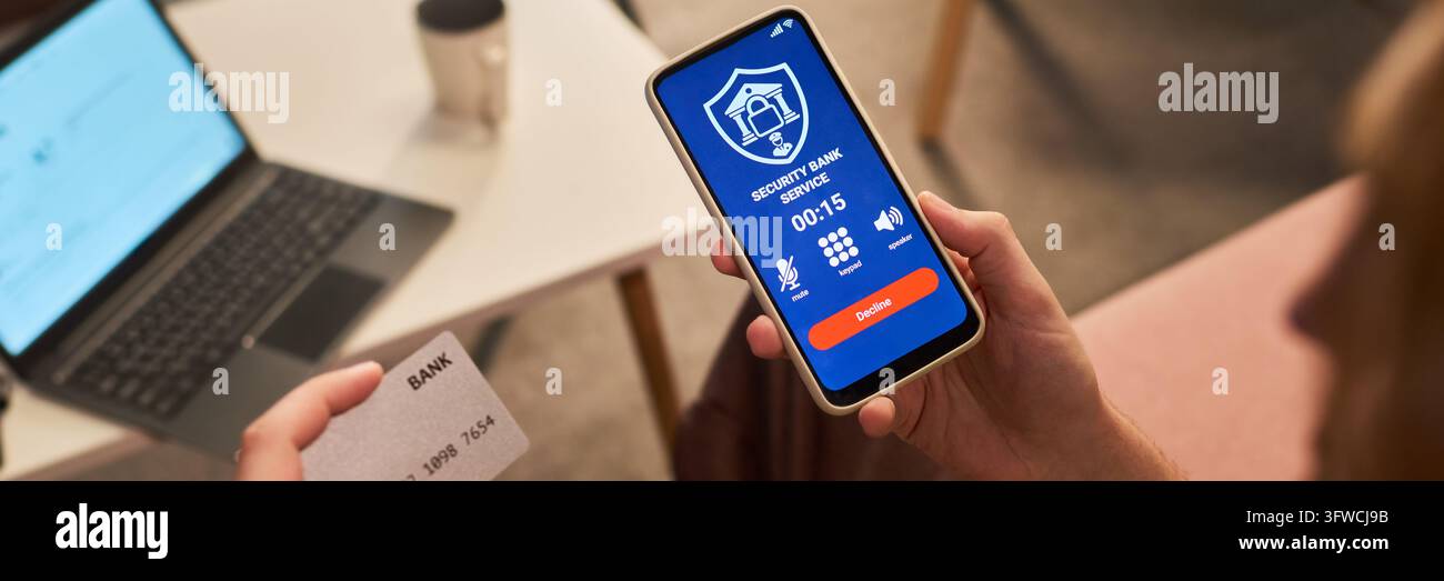 Uomo che tiene uno smartphone durante una chiamata di sicurezza della banca a casa Foto Stock