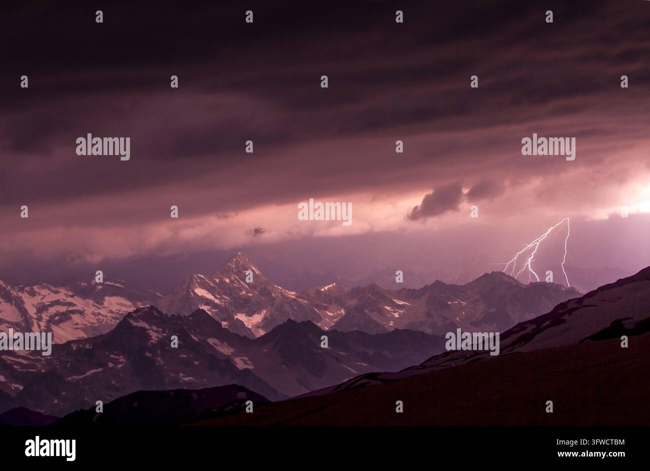 Tempesta drammatica di fulmini illumina le cime innevate delle montagne Foto Stock
