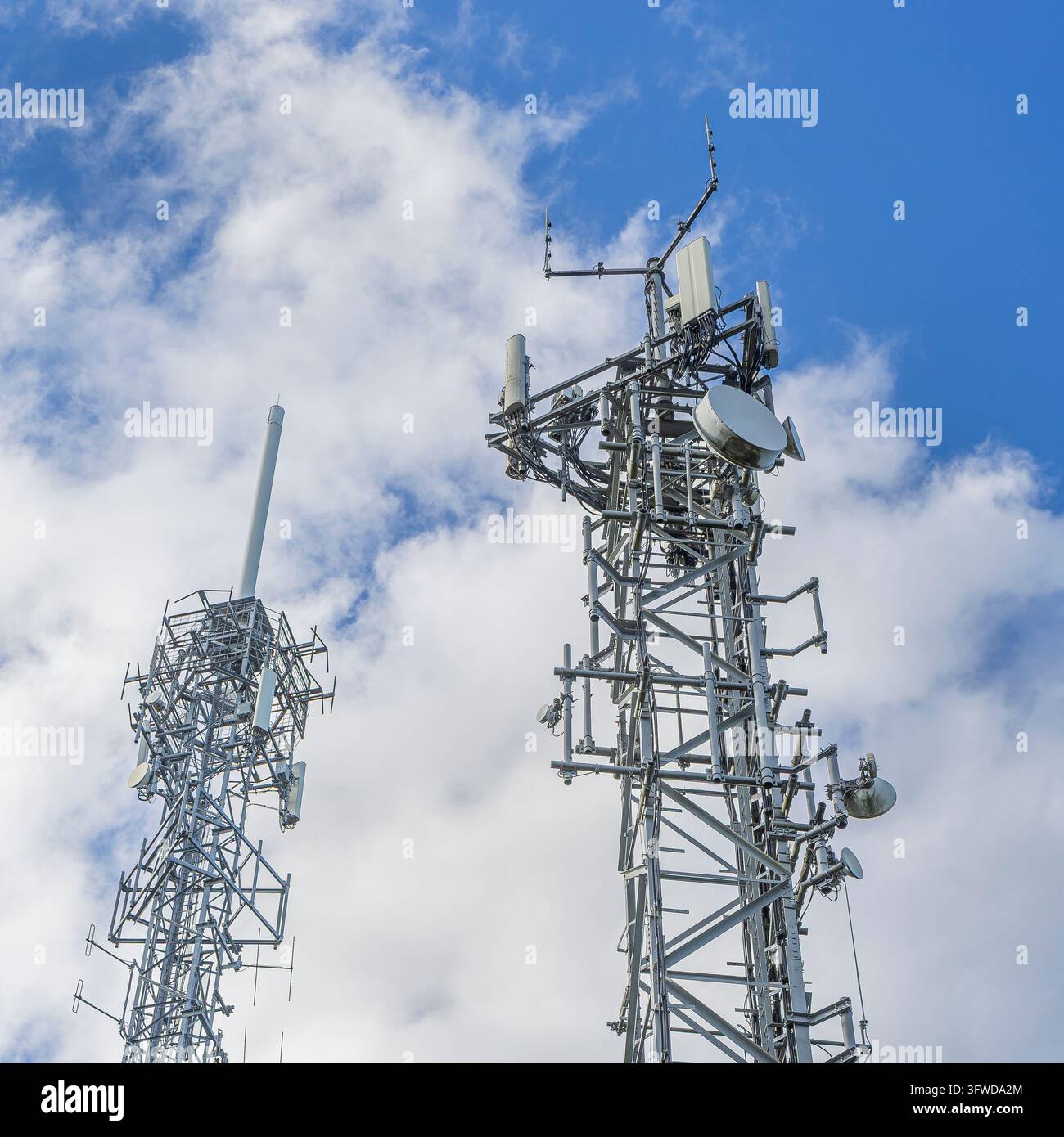 Vista ravvicinata di due tralicci per telefoni mobili con pannelli di varie dimensioni.. Foto Stock