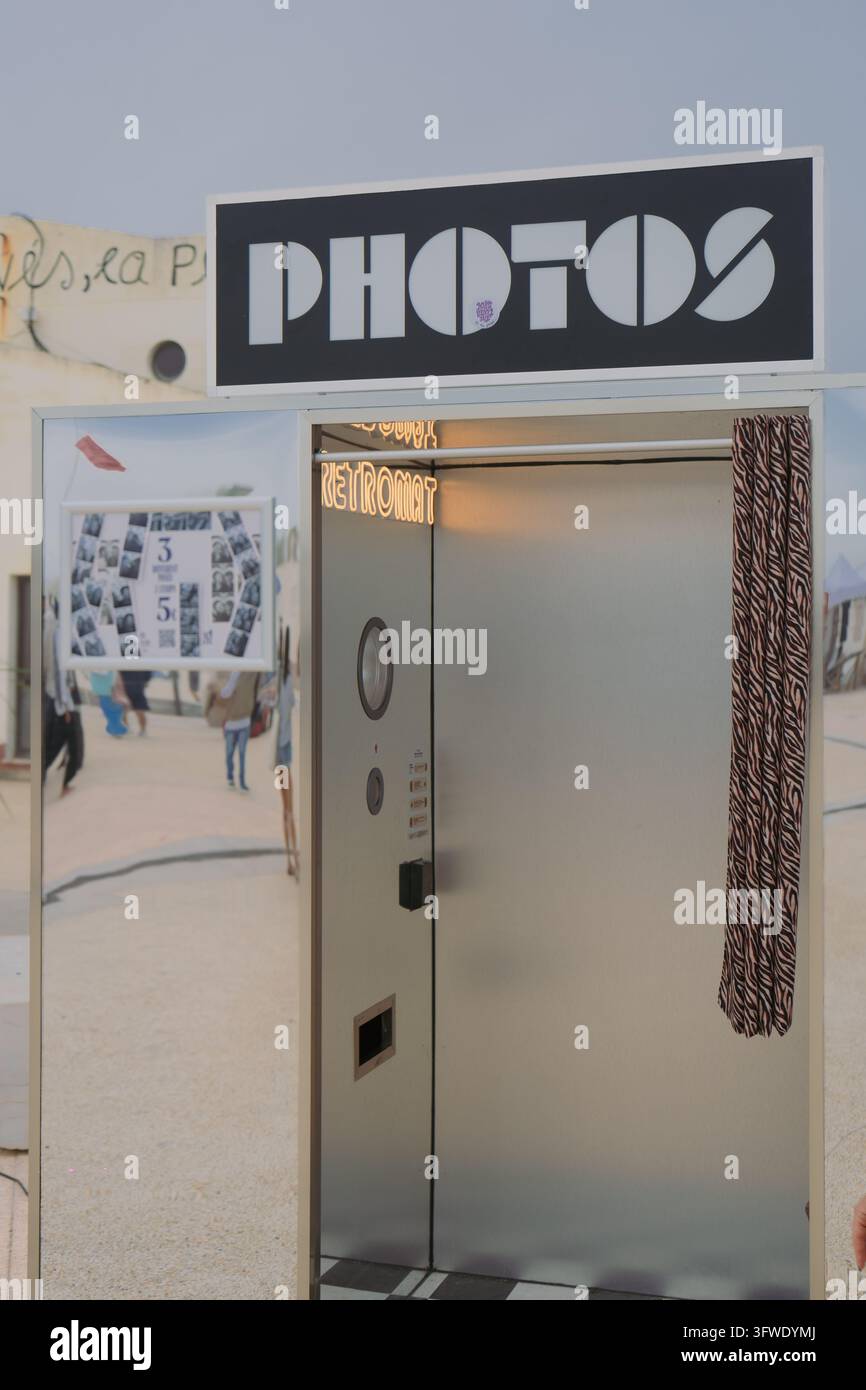 Cabina fotografica retrò in argento stilizzata in piedi all'aperto in una giornata estiva soleggiata, catturando l'estetica vintage e la cultura fotografica nostalgica. Foto Stock