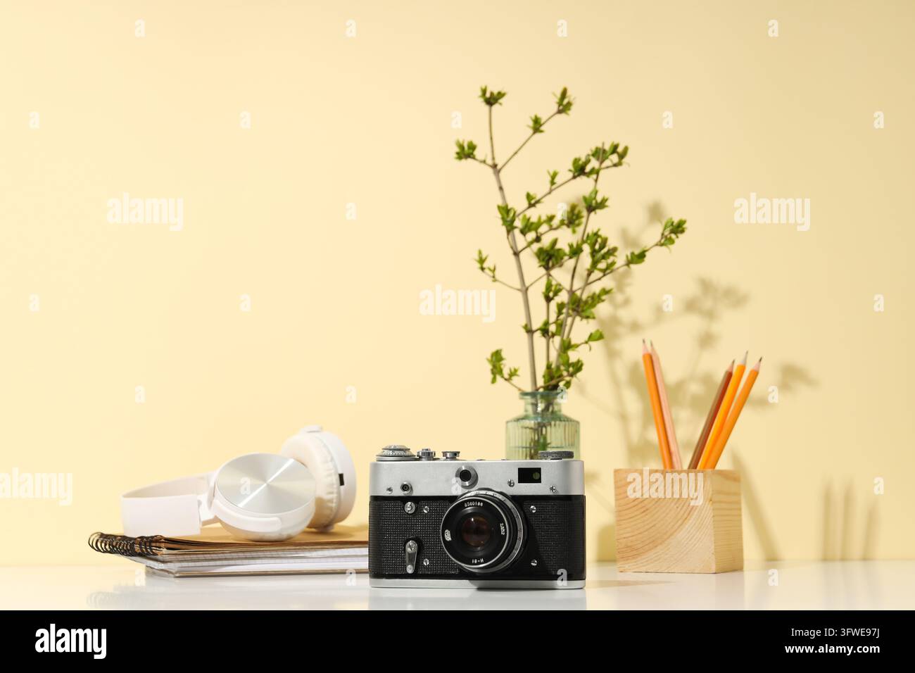 Fotocamera vintage, cuffie e matite su sfondo beige Foto Stock