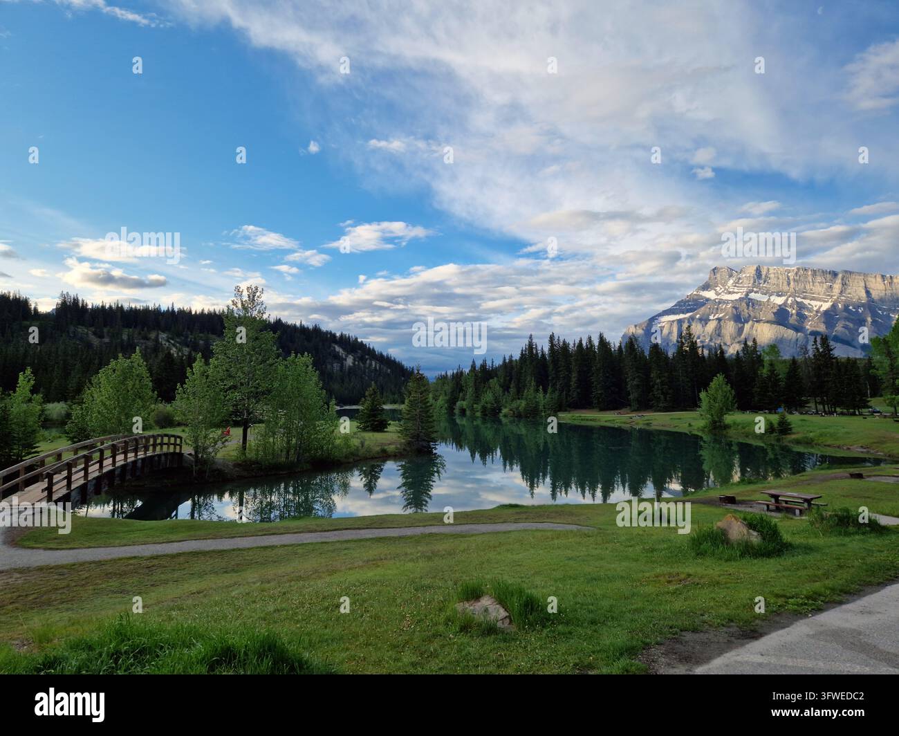 Vista del lago Two Jack con una passerella di legno, pini e riflessi delle montagne nell'acqua nel Parco Nazionale di Banff nel Distretto di Miglioramento n. 9 Foto Stock