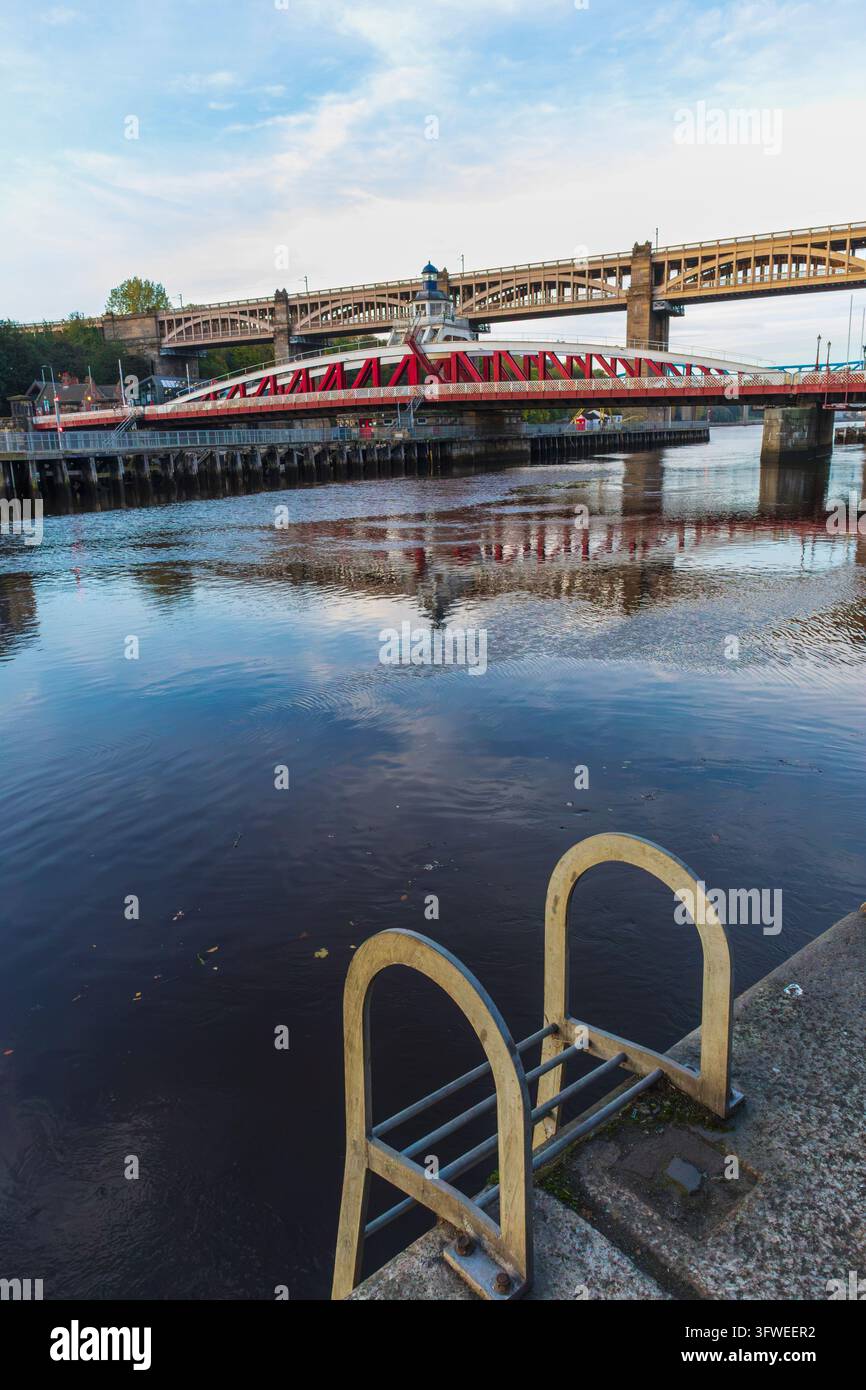 Ponte oscillante con ponte ad alto livello sullo sfondo attraverso il fiume Tyne Foto Stock