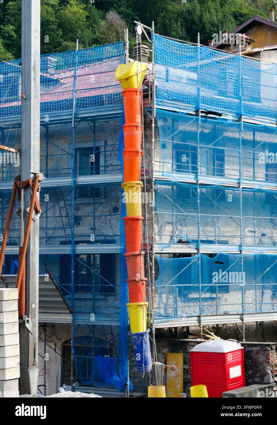 Edificio residenziale in ristrutturazione con scarico dei detriti e involucro di impalcatura Foto Stock