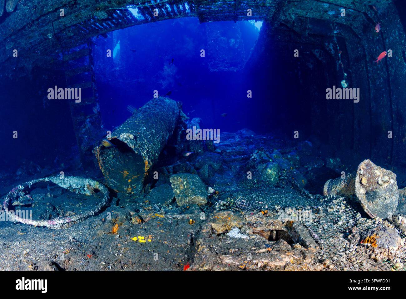 Interno della stiva del relitto di Boga vicino a Tulamben, Bali, tubi metallici affondati e detriti strutturali ricoperti di vita marina sul fondo del fondale marino Foto Stock