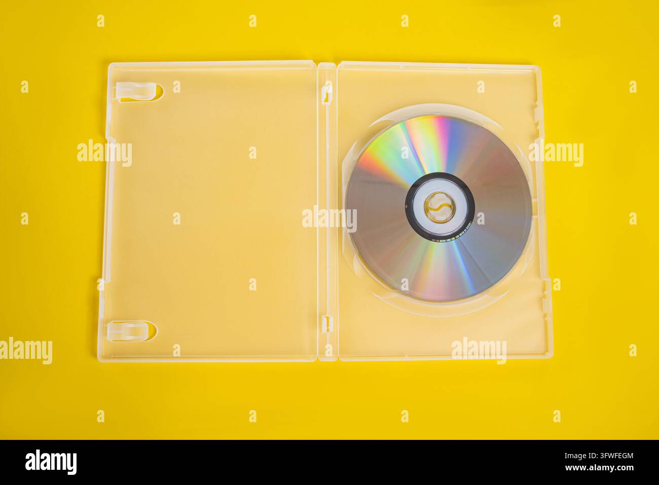Una custodia DVD o Blu-ray in plastica aperta e trasparente è mostrata su uno sfondo giallo vibrante, che mette in risalto un disco ottico riflettente all'interno. Foto Stock