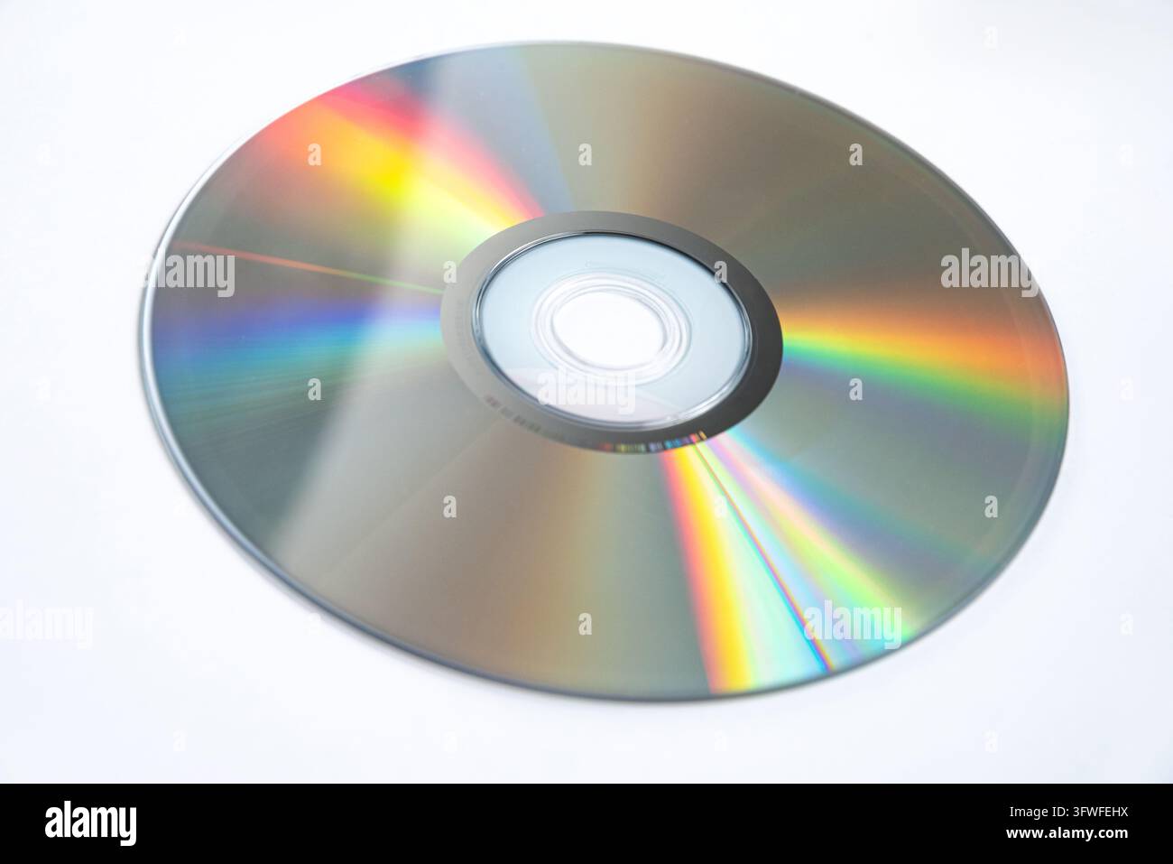 Un primo piano in studio di un compact disc argentato con riflessi visibili dello spettro arcobaleno sulla sua superficie, evidenziando le proprietà ottiche e i dettagli Foto Stock