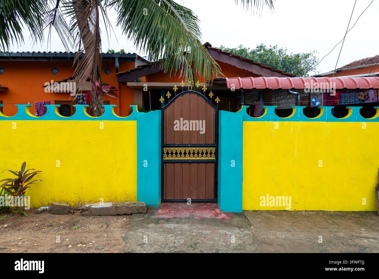 Muro giallo brillante e turchese con un cancello di legno, Provincia Settentrionale, Jaffna, Sri Lanka Foto Stock