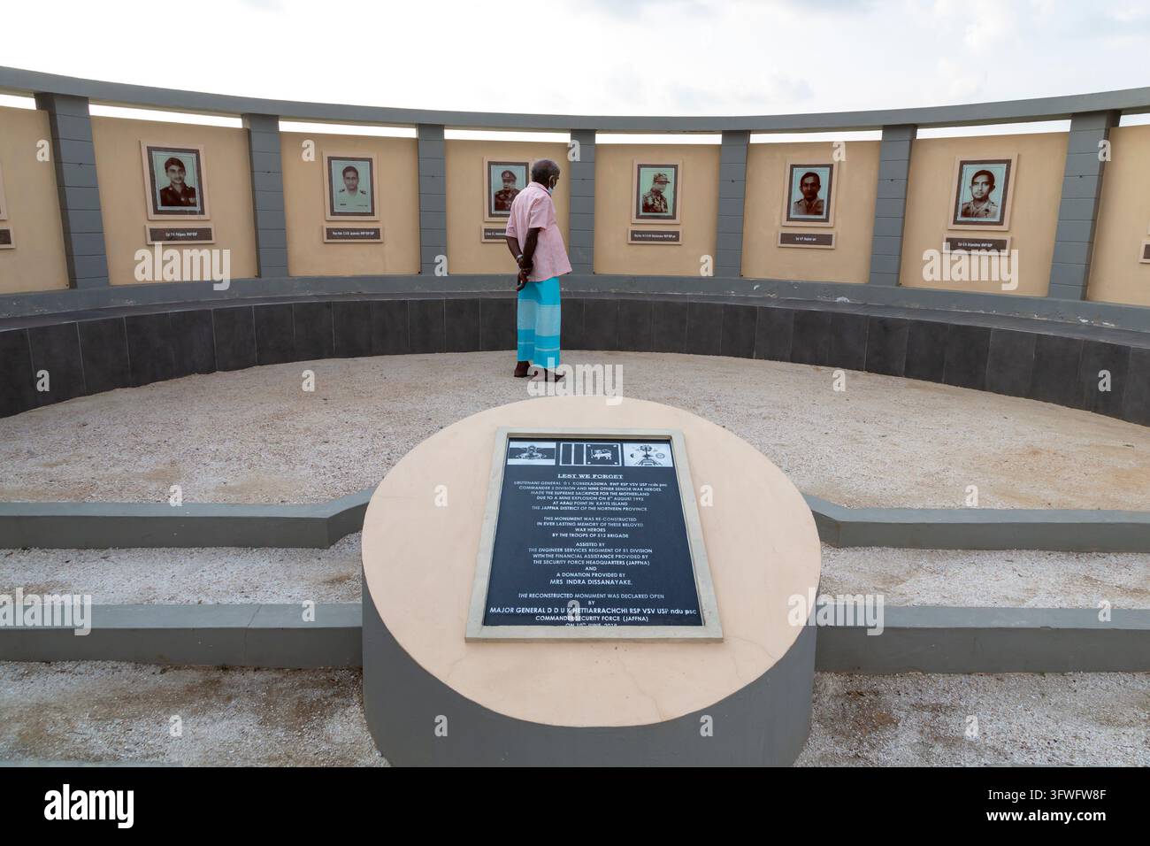 Uomo che osserva ritratti di soldati su un muro commemorativo curvo del dopoguerra, Provincia Settentrionale, Jaffna, Sri Lanka Foto Stock