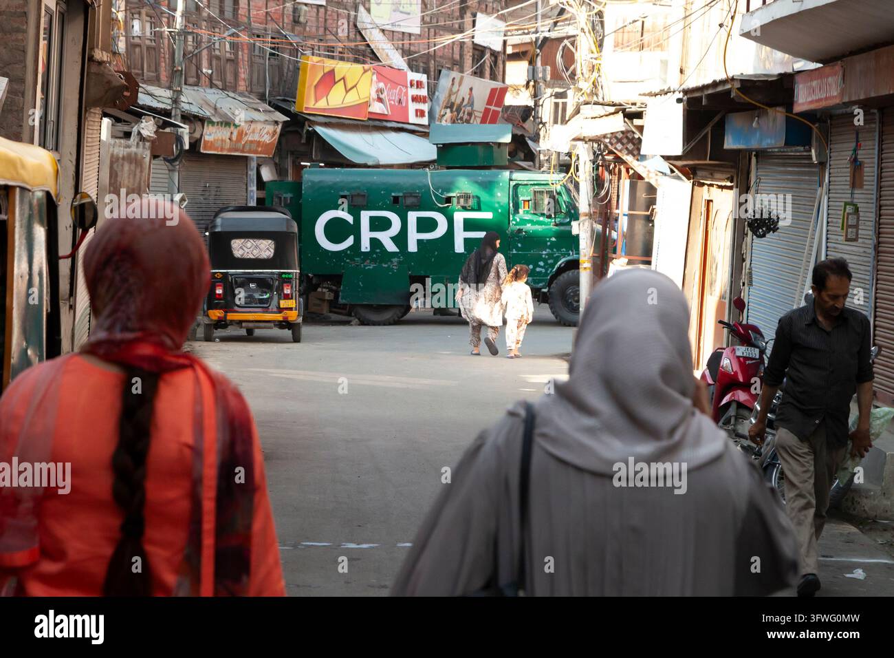 Donne che camminano verso un veicolo blindato della Central Reserve Police Force in una strada, Jammu e Kashmir, Srinagar, India Foto Stock
