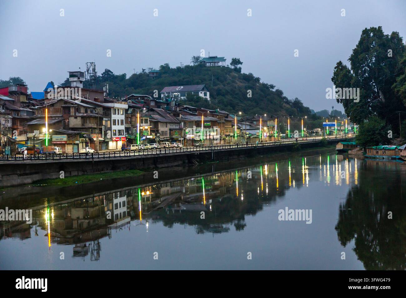 Arginino del fiume con pali illuminati riflessi nell'acqua al crepuscolo, Jammu e Kashmir, Srinagar, India Foto Stock