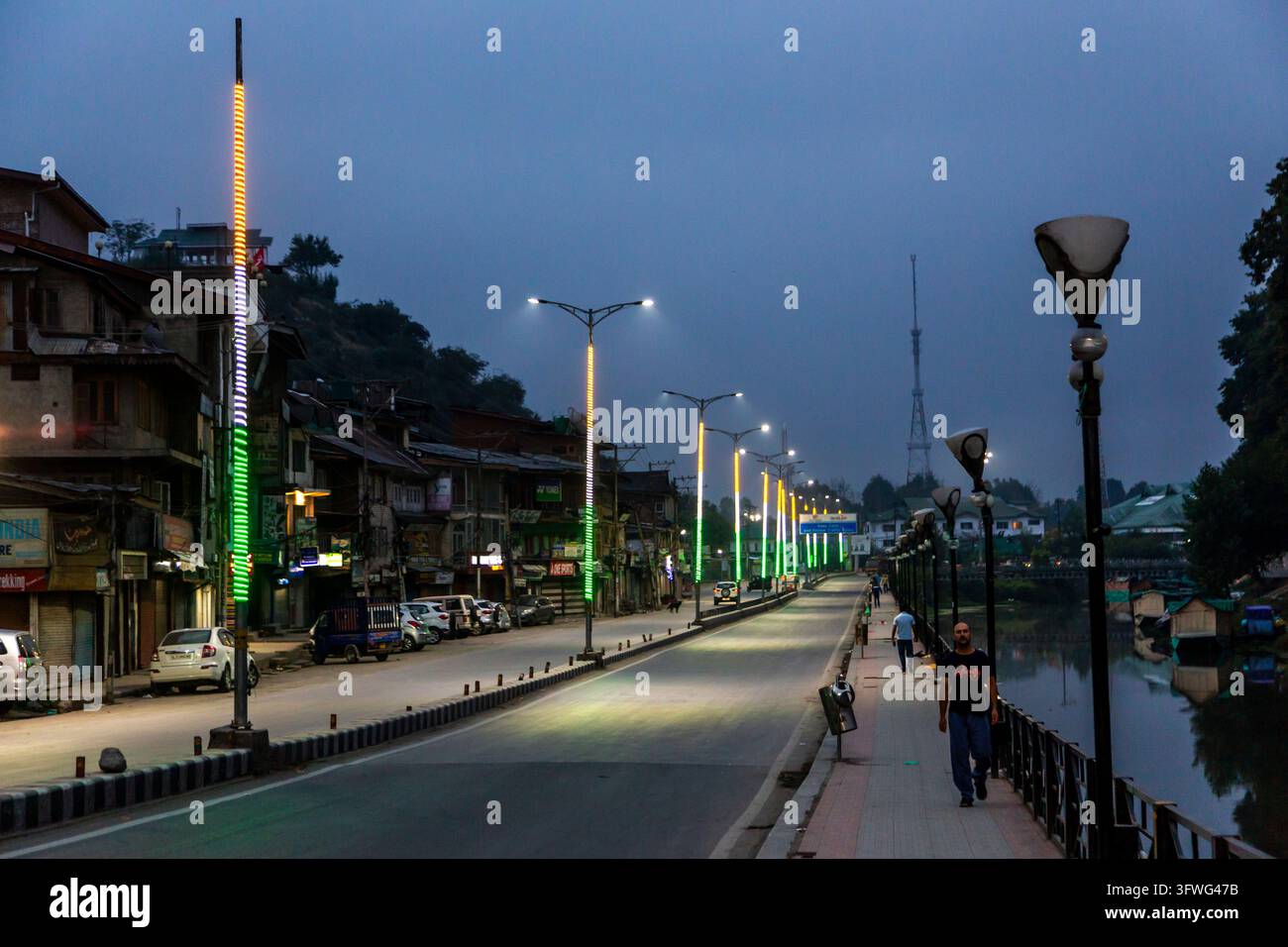 Strada riverside e passeggiata deserte con pali illuminati al crepuscolo, Jammu e Kashmir, Srinagar, India Foto Stock