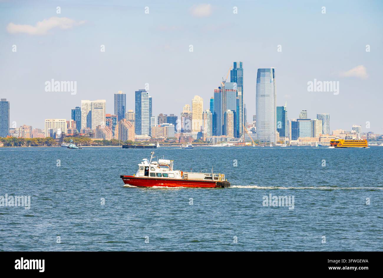New York, USA - 25 settembre 2026: Barca di soccorso rossa e bianca che naviga sull'Hudson River con lo sfondo degli skyscrapers di Lower Manhattan a NYC Foto Stock