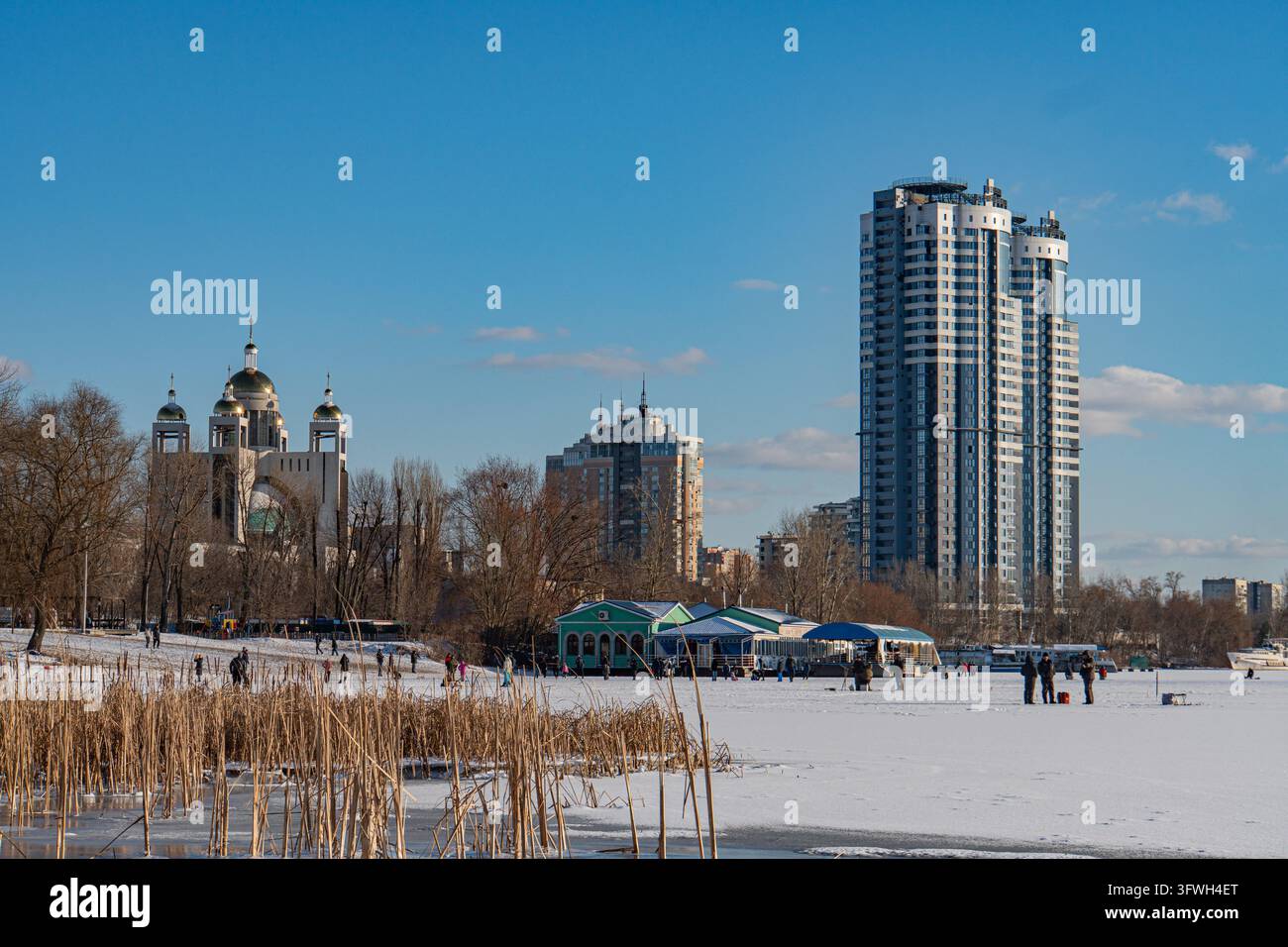 Paesaggio invernale di Kyiv con un grattacielo moderno prominente, area aperta innevata, tende per eventi temporanee, luce naturale brillante, veduta della città di Kyiv, Ucraina Foto Stock