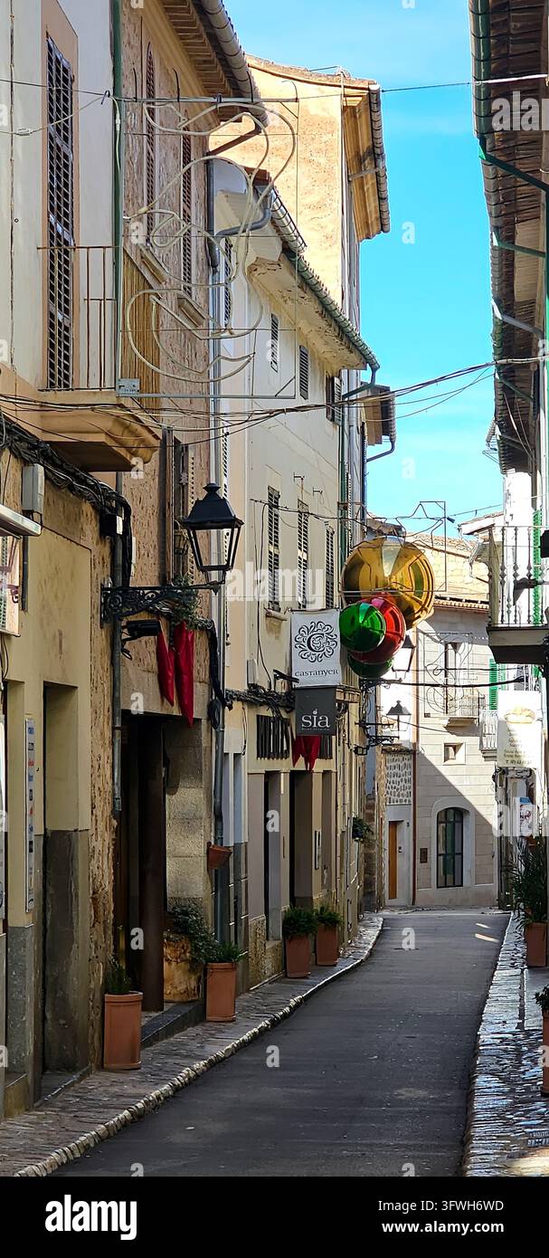 Accogliente vicolo con piante in vaso, edifici tradizionali e decorazioni natalizie colorate appese sopra il percorso stretto. vicolo, decorazione. Foto Stock