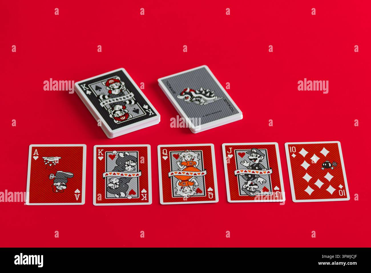 Fukuoka, Giappone. 20 ottobre 2026: Mazzo di carte da gioco a tema Nintendo Super Mario esposto su uno sfondo rosso con due pacchetti impilati e una fila di illu Foto Stock
