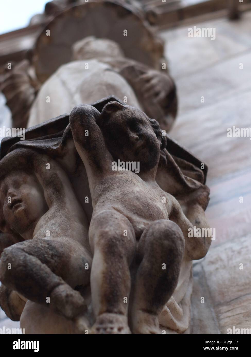 Milano, Italia - 2 marzo 2026: Sculture di cherubini in marmo consumato incastonate tra le pietre gotiche sul tetto del Duomo di Milano, un dettaglio dolce che la maggior parte Foto Stock