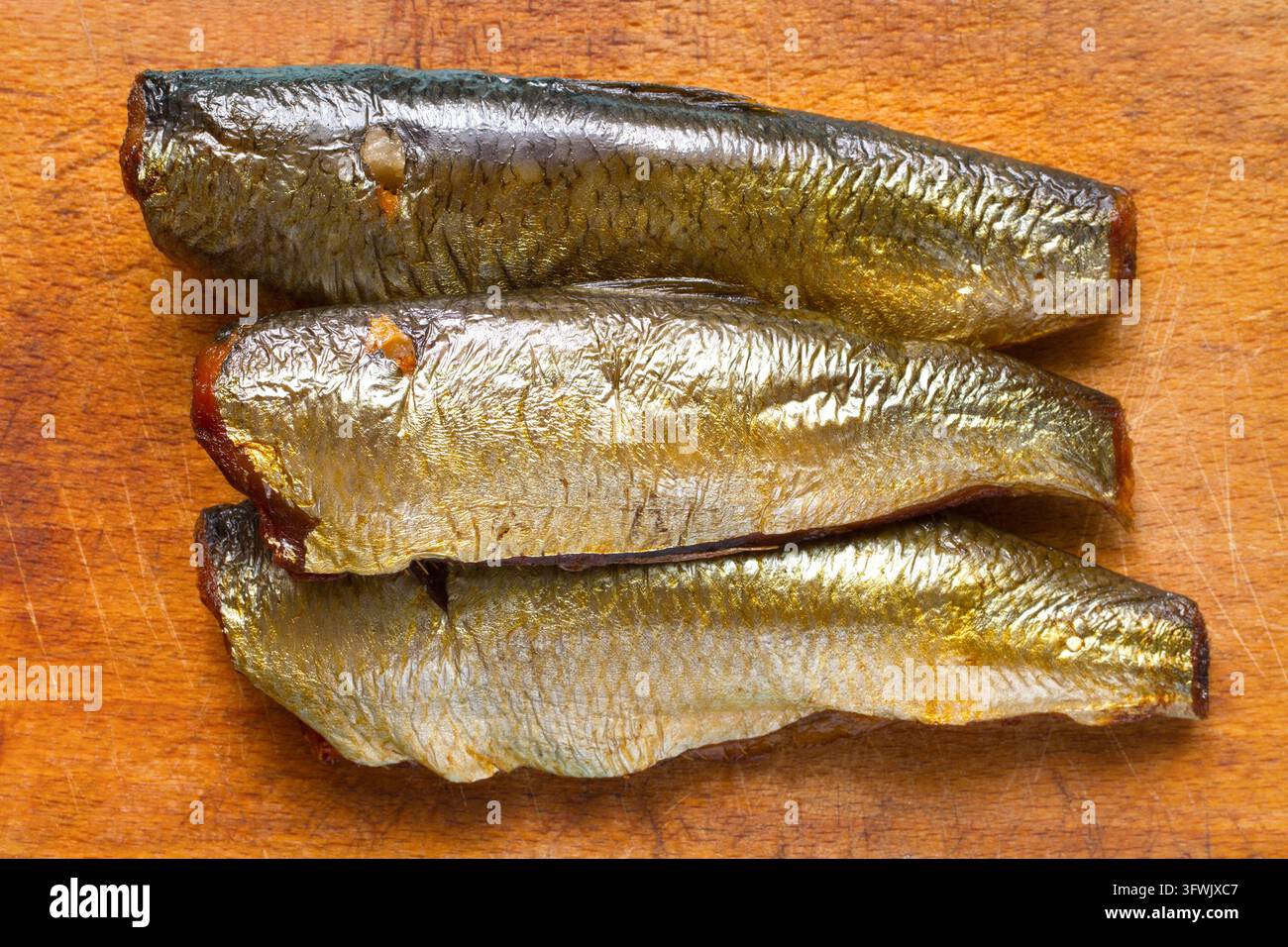 Tre pesci affumicati su un tagliere di legno. Pesce affumicato fresco. Foto Stock