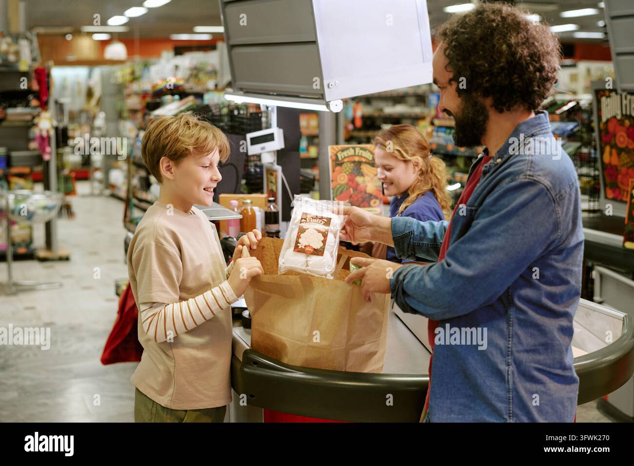Padre e figlio che mettono la spesa in un sacchetto di carta al supermercato Foto Stock
