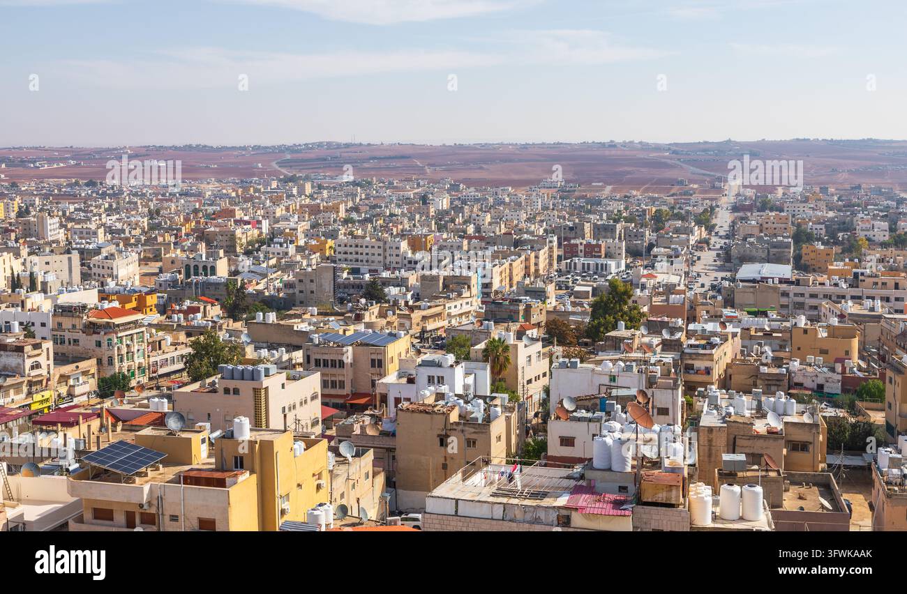 Veduta aerea della città di Madaba, con architettura urbana densa, tetti piatti con serbatoi d'acqua e un vasto paesaggio desertico a Madaba, Madaba G Foto Stock