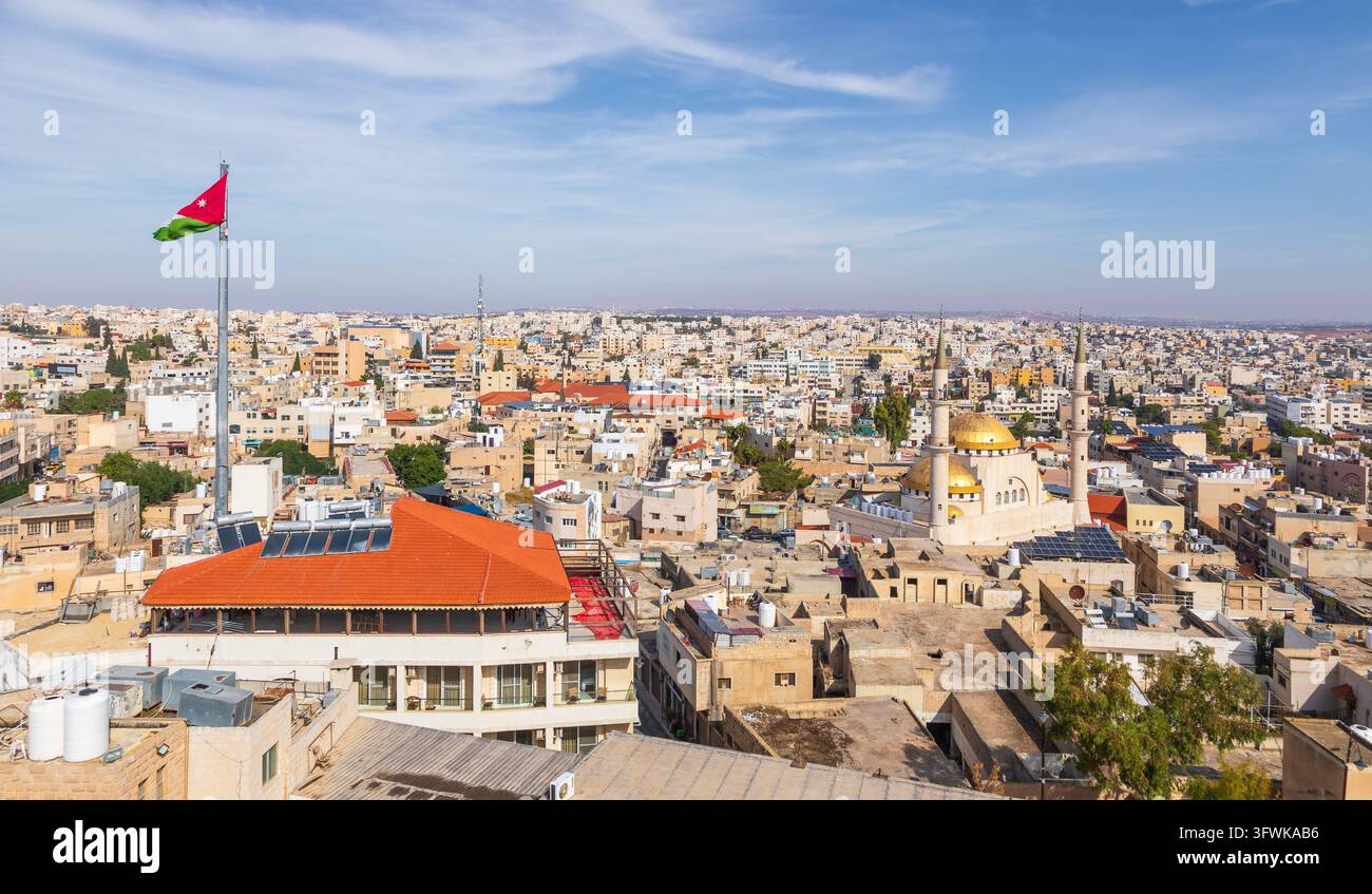 Vista aerea della città di Madaba, che mostra la cupola dorata di una moschea, un alto asta della bandiera con la bandiera giordana e tetti urbani fitti a Madaba Foto Stock