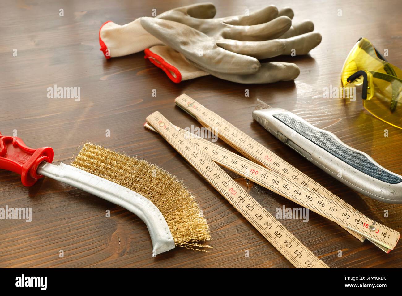 Strumento con spazzola metallica per la rimozione della ruggine e la preparazione della superficie su un banco da lavoro in legno. Pulizia del metallo, pulizia manuale della ruggine, attrezzatura per il restauro. Superficie Foto Stock