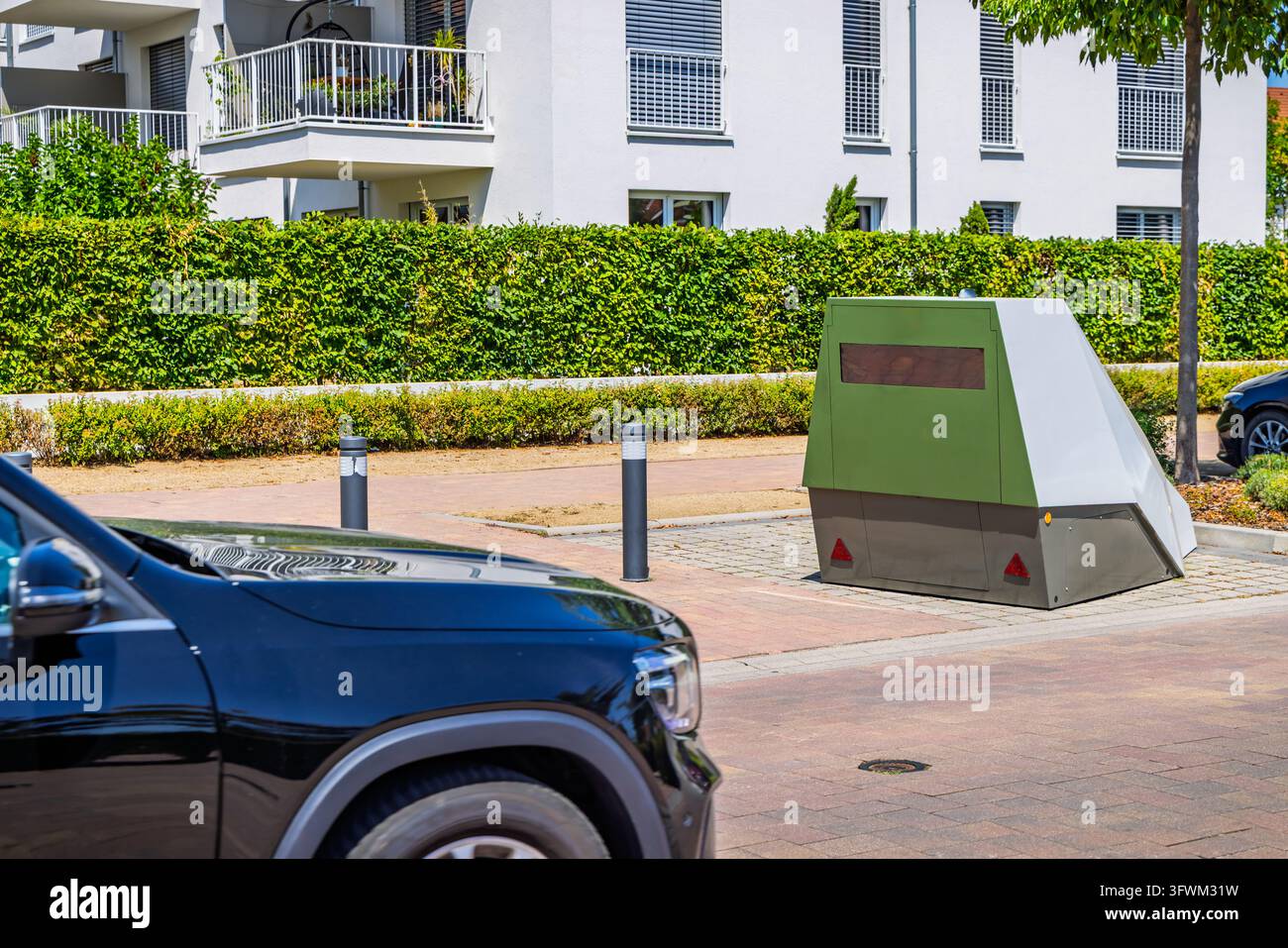 Telecamera mobile per il controllo della velocità su una strada urbana accanto ad appartamenti e veicoli parcheggiati Foto Stock